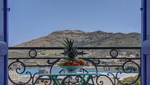A balcony with a fruit bowl and a view of a beach and mountains.