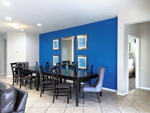 A dining area with a dark wooden table, six chairs, and a large mirror on a blue wall.