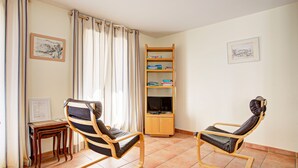 A room with two reclining chairs, a wooden bookshelf, a television, and a small table.