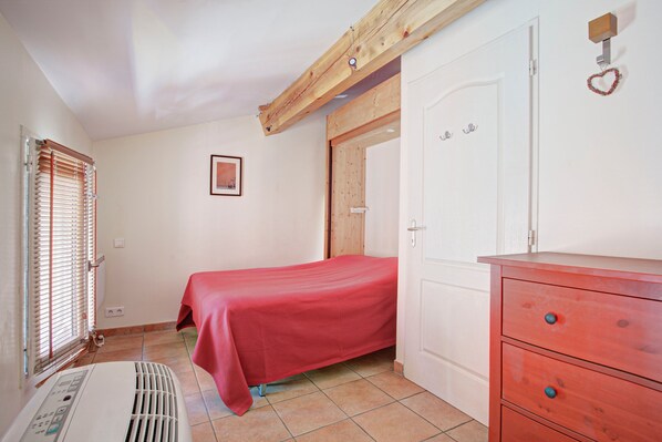 Une chambre à coucher avec un lit, un radiateur, une armoire et une porte.