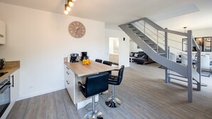 A modern kitchen with a wooden island, bar stools, and a clock on the wall.