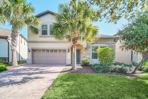 A two-story house with a garage, a well-maintained lawn, and various plants and shrubs.