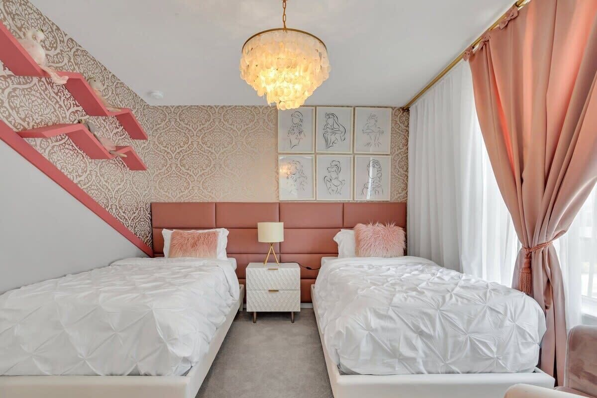 A bedroom with two beds, a chandelier, a nightstand, and a patterned wall.