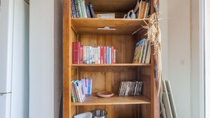 Une bibliothèque en bois remplie de livres, un seau en métal et un pichet blanc.