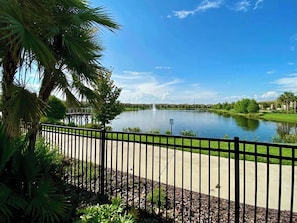 A serene lake with a fountain, surrounded by lush greenery and a clear blue sky. - Pool Table! Lazy River! Resort 6 mi 2 Disney! 9045 (Kissimmee)