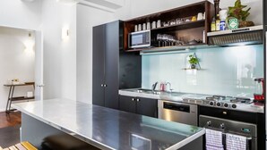 A modern kitchen with a central island, built-in microwave, and stainless steel appliances. - Gorgeous NY Style Loft in CBD | Netflix Wifi | (Auckland CBD)