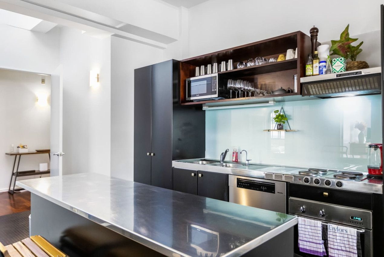 Una cocina moderna con una isla central, microondas integrado y electrodomésticos de acero inoxidable.