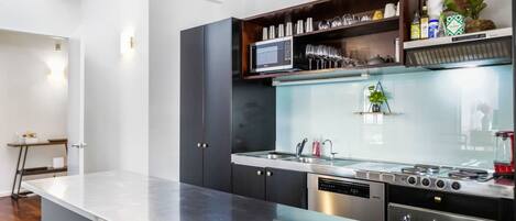 Una cocina moderna con una isla central, microondas integrado y electrodomésticos de acero inoxidable.