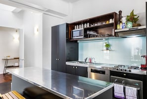 A modern kitchen with a central island, built-in microwave, and stainless steel appliances.