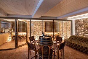 A room with a stone wall, a wine rack, a round wooden barrel, and a tufted sofa. - Casa Rotunda (Whitsundays)