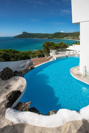 Une piscine avec vue sur la mer et un paysage montagneux.