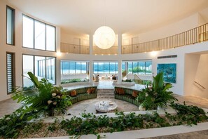 A spacious interior with a central seating area, large windows, and a view of the outdoors. - Casa Rotunda (Whitsundays)