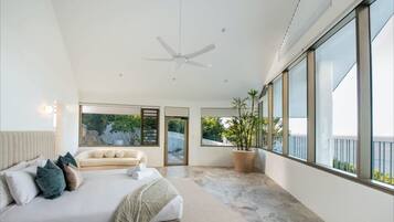 A modern bedroom with a large bed, a ceiling fan, and a potted plant.