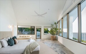 A modern bedroom with a large bed, a ceiling fan, and a potted plant. - Casa Rotunda (Whitsundays)