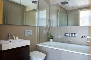 Un baño moderno con ducha envuelta en vidrio, lavamanos blanco y un inodoro.