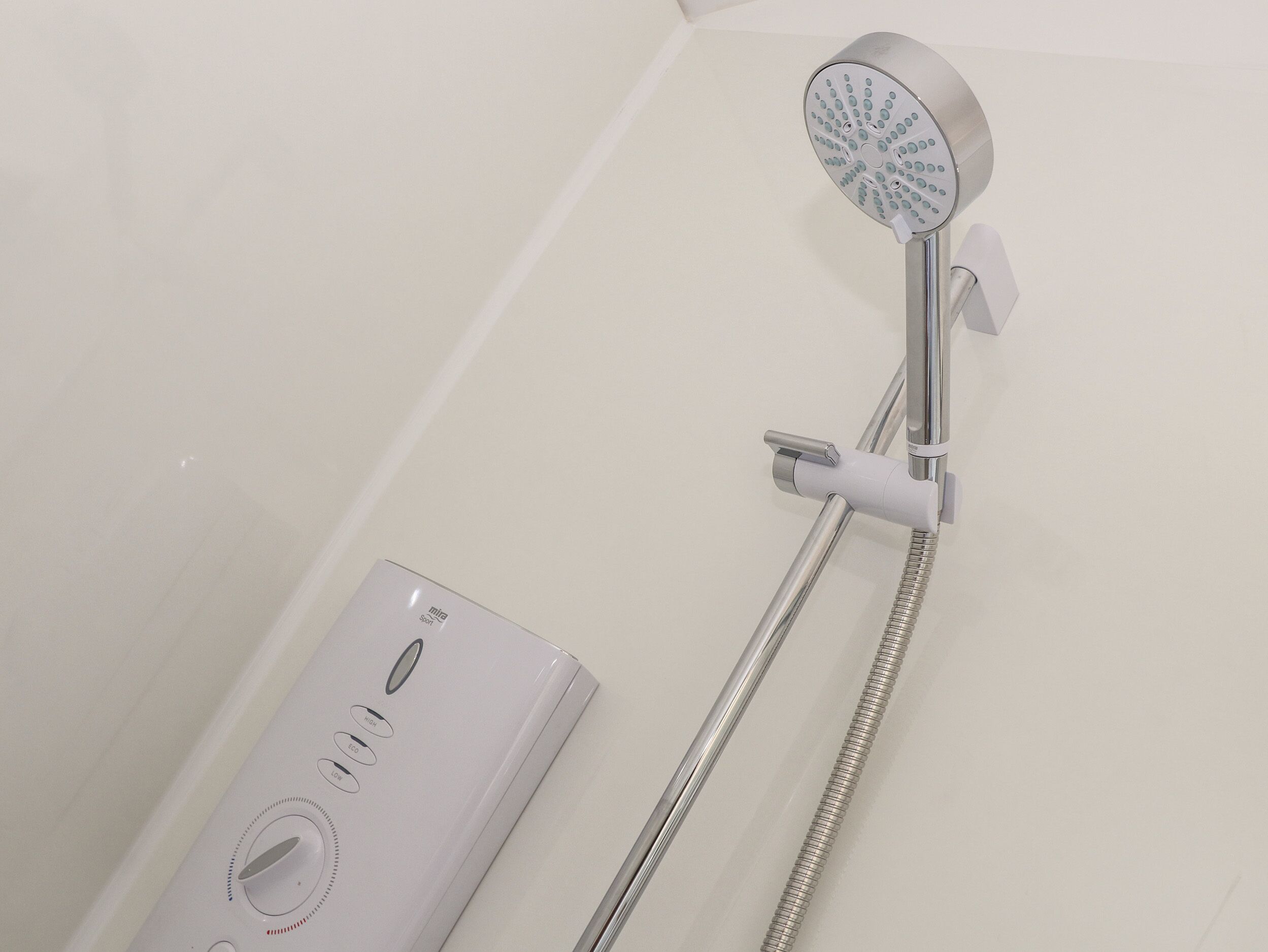 A modern shower with a handheld control unit and a handheld showerhead.