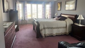 Un dormitorio con cama, cómoda, escritorio y ventilador de techo.