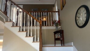Una escalera con barandillas de madera y un reloj fijado a la pared.