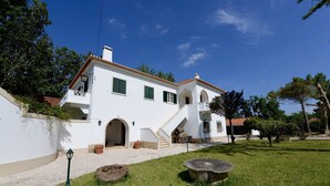 A white building with a tiled roof, a staircase, and a paved courtyard.