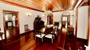 A spacious dining area with a long wooden table, six chairs, and a chandelier.