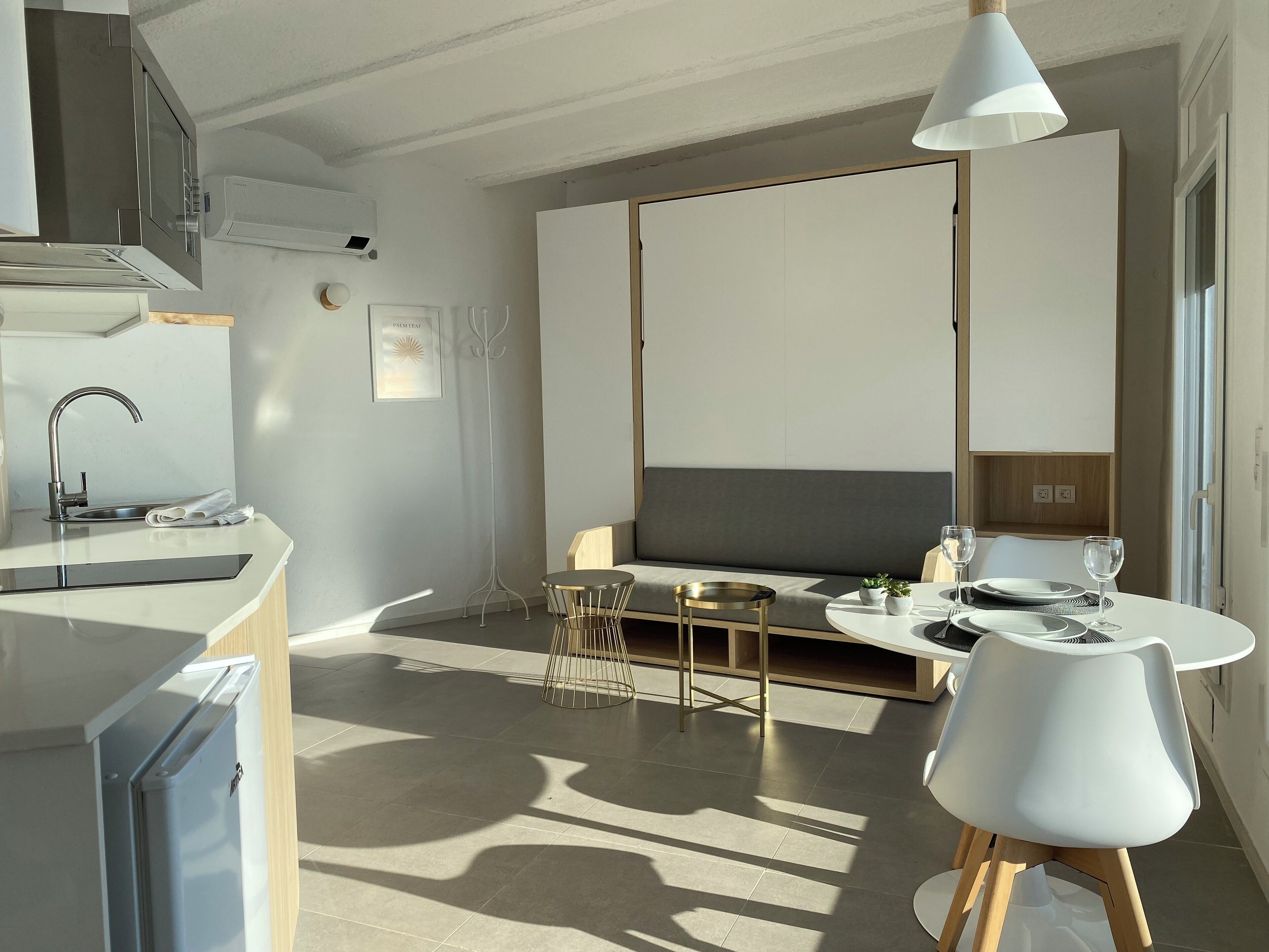 Ett modernt kök med en inbyggd ugn, en diskho och en matplats med ett bord och stolar.