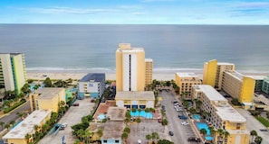 Ein Küstenhotel mit einem zentralen Gebäude, einem Schwimmbad und Blick auf den Strand.