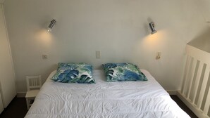 A neatly made bed with white bedding and two decorative pillows with a tropical leaf pattern. - CROMLEC'H - Duplex, Aperçu Mer - DT170 (Carnac)