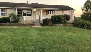 A single-story house with a front porch, a chimney, and a well-maintained lawn.