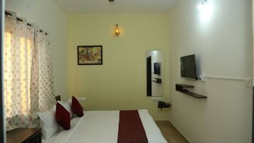 Una habitación de hotel con una cama, televisión, estante en la pared y un cuadro.