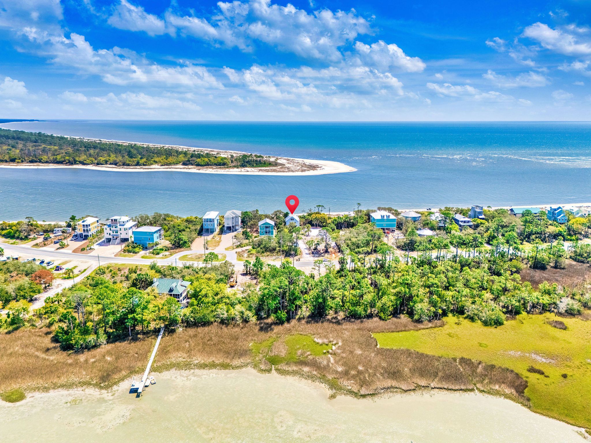 An aerial view of a coastal area with a mix of residential buildings and natural landscapes.