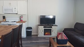 Una sala de estar con televisión, chimenea y comedor con estufa.