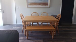 Un comedor con una mesa y sillas de madera, un banco y un cuadro en la pared.
