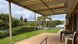 A covered patio with a table and chairs, brick steps, and a view of the surrounding greenery and hills. - The EOS 2, Esperance (Esperance)