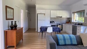 A modern, open-plan living and dining area with a kitchen, wooden flooring, and a grey sofa. - The EOS 2, Esperance (Esperance)