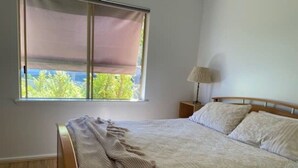 A bedroom with a bed, a window with a blind, a nightstand, and a lamp. - The EOS 2, Esperance (Esperance)