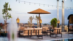 Un área de piscina en la azotea con mobiliario exterior, una pérgola y lámparas decorativas.