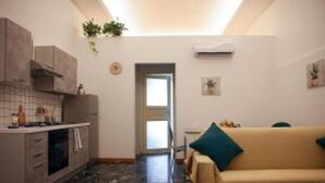 Un espacio habitable compacto con kitchenette, un sofá y un pequeño comedor.