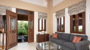 A spacious living room with a grey sofa, a glass coffee table, and a wooden cabinet. - Villa Elounda Plaka - Three Bedroom Villa, Sleeps 6 (Plaka)