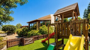 Un parque infantil con toboganes y una casita de madera.