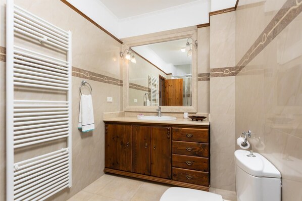 A bathroom with a white radiator, wooden vanity, and a large mirror.