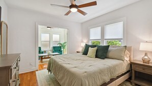 Un dormitorio con cama, mesita de noche y ventilador de techo.