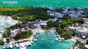 An aerial view of Bayahibe Village with clear turquoise waters, a beach, and a marina. - Tribe Inn & Rooftop Lounge (San Rafael del Yuma)