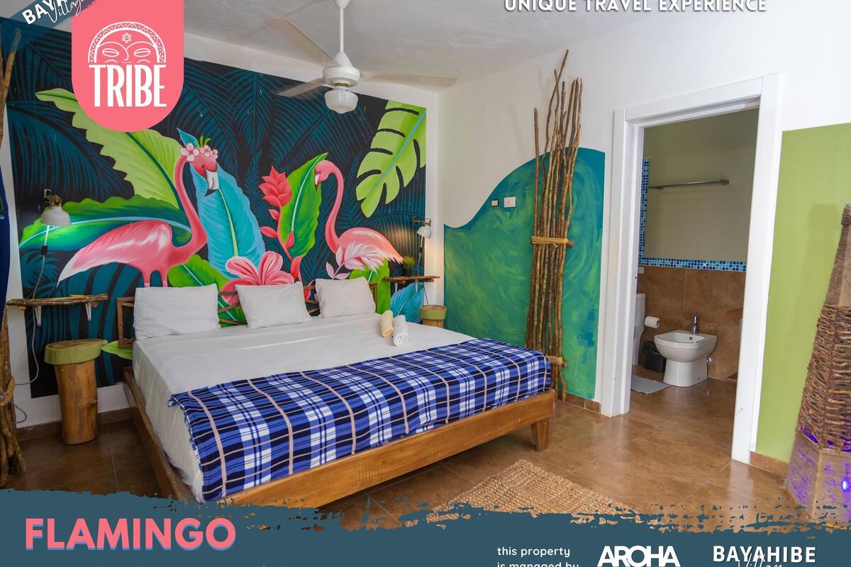 A large room with a bed, a ceiling fan, and a wall mural of flamingos.