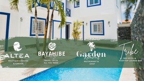A white building with blue trim and windows, a pool, and palm trees. - Tribe Inn & Rooftop Lounge (San Rafael del Yuma)