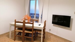 A dining area with a table and chairs, a TV mounted on the wall, and a window with curtains. - Bright and comfortable, it offers a wonderful view from the sea-facing terrace.  (Viareggio)