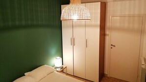 A bedroom with a bed, a wardrobe, a nightstand with a lamp, and a hanging light fixture. - Bright and comfortable, it offers a wonderful view from the sea-facing terrace.  (Viareggio)