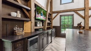 Une cuisine avec des poutres en bois, une grande fenêtre et un téléviseur posé sur une étagère en bois.