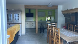 A modern kitchen with a central island, wooden chairs, and a dining table. - Ferme Familiale Rénovée Dans un Village Tranquille (La Vendeix, GELLES)