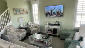 A living room with a sofa, armchairs, a coffee table, and a television.