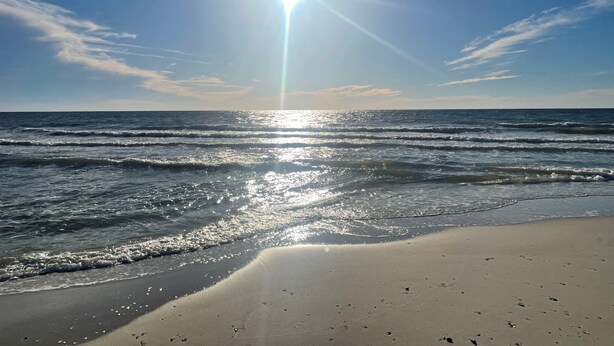 A beach with waves and a clear sky.